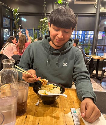 Giovanni Romero uses chopsticks to eat food at a restaurant.