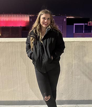 Grace Steffes stands near the edge of a parking garage in Detroit while posing for a photo.